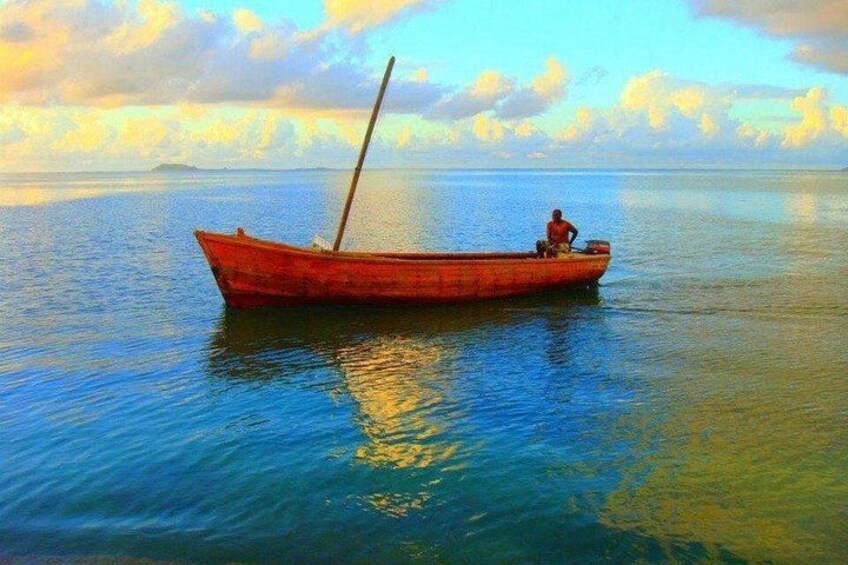 Un bateau rouge sur une eau calme, avec une personne assise à l’avant. 5