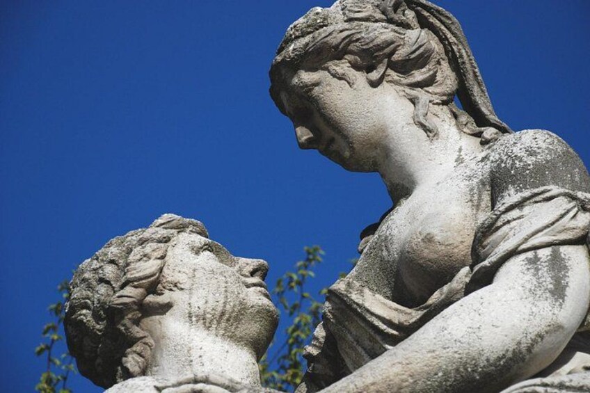 A stone sculpture of a woman with a child, set against a clear blue sky. 5