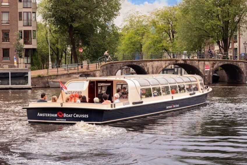 Un bateau baptisé « Amsterdam Boat Cruises » navigue sur un canal, avec un pont en arrière-plan. 2