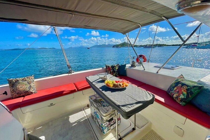 Een dek van een boot met een tafel, kussens en uitzicht op zee. 1