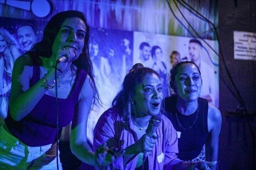 A person holding a microphone, another person in a purple top, and a third person in a black top. 5
