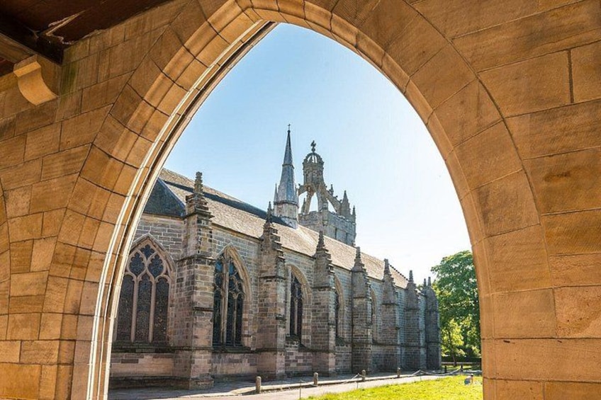 A stone archway framing a historic church with pointed arches and a spire. 3