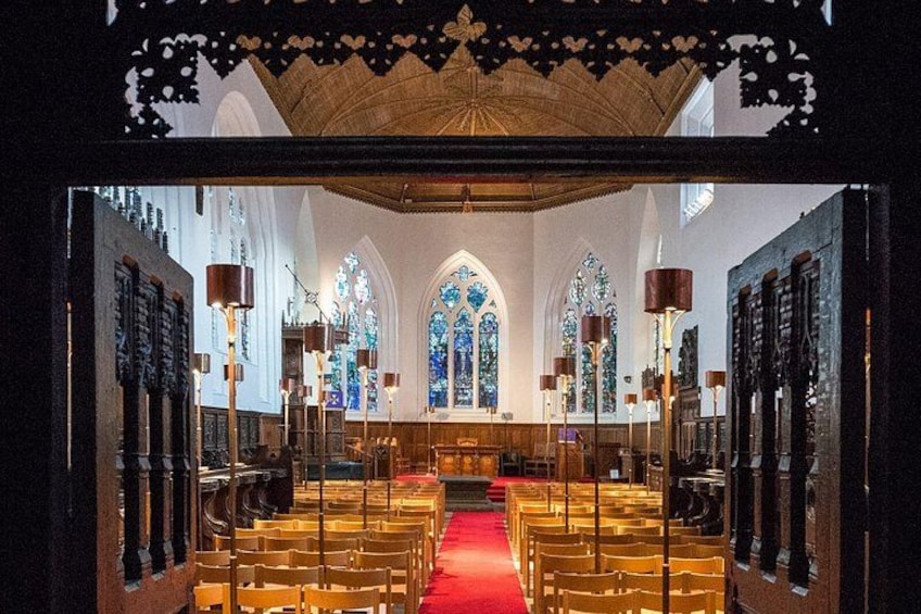 A church interior with rows of pews, stained glass windows, and a red carpet. 2