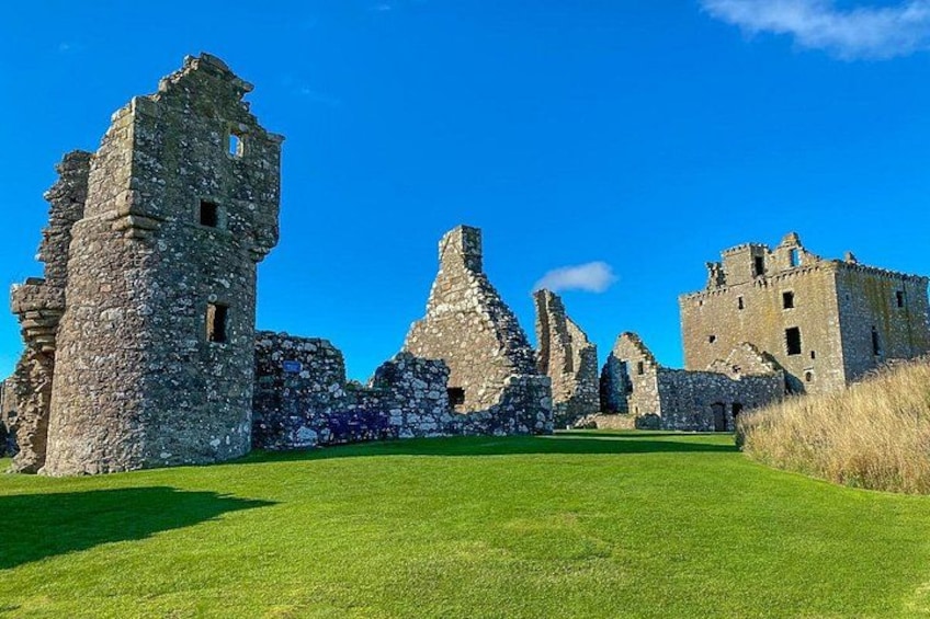 A historic stone castle ruin with grassy fields. 4