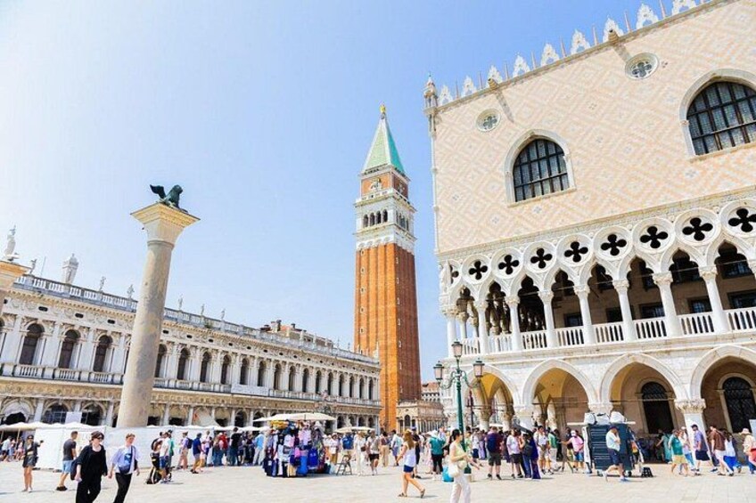 A historic square with a prominent tower, a statue, and ornate buildings. 2