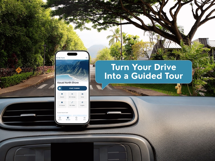A smartphone mounted on a car dashboard displaying a guided tour app for Kauai North Shore. 3