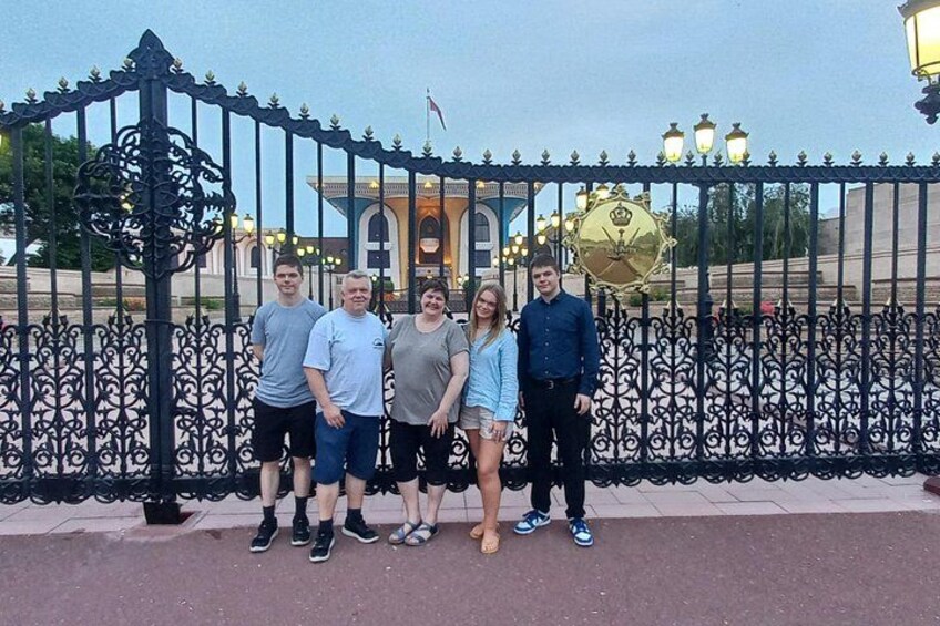 A group of people standing in front of a decorative iron fence with a building in the background. 3