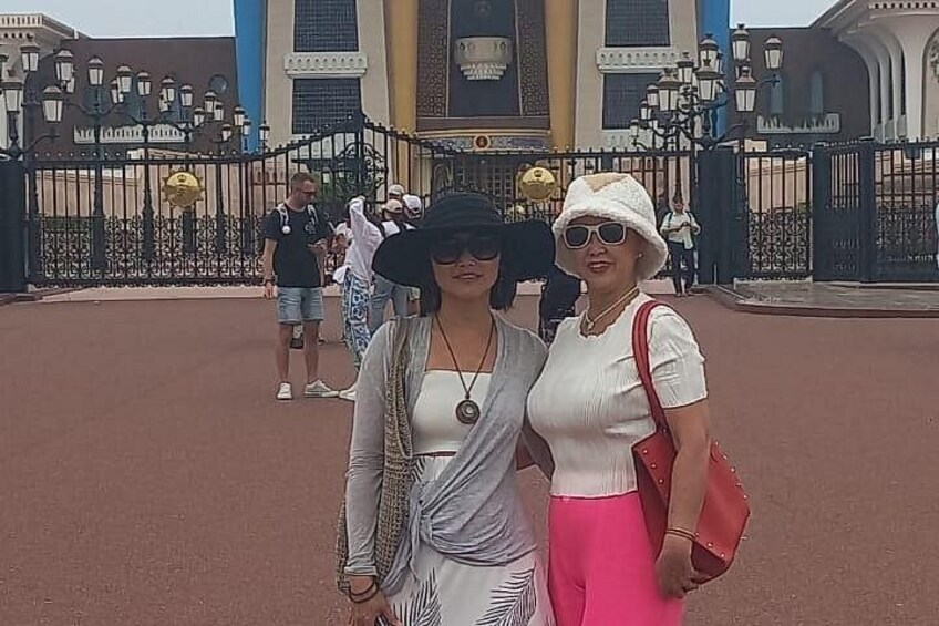 Two people standing in front of a gate with a building in the background. 5
