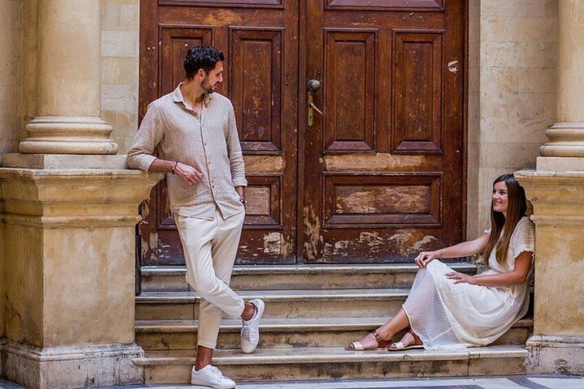 Ein Mann in einer beigen Hemde und Hose, eine Frau in einem weißen Kleid und eine Holztür mit Messingknauf. 5
