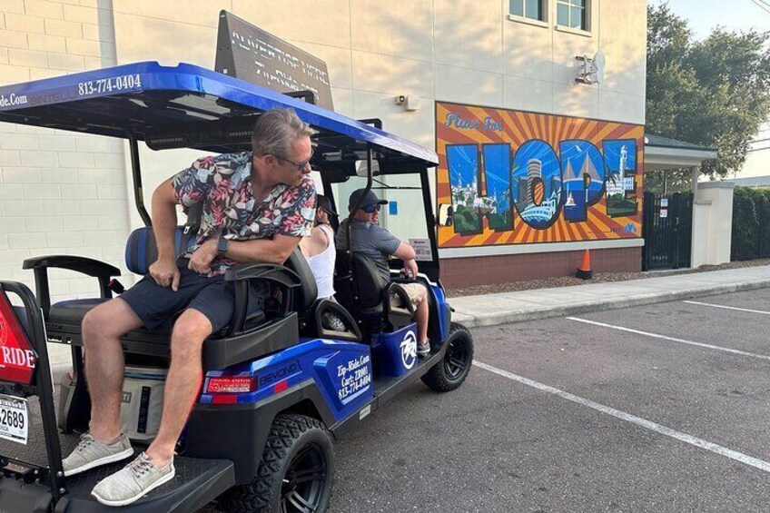 A golf cart with a blue canopy parked in a parking lot. 1