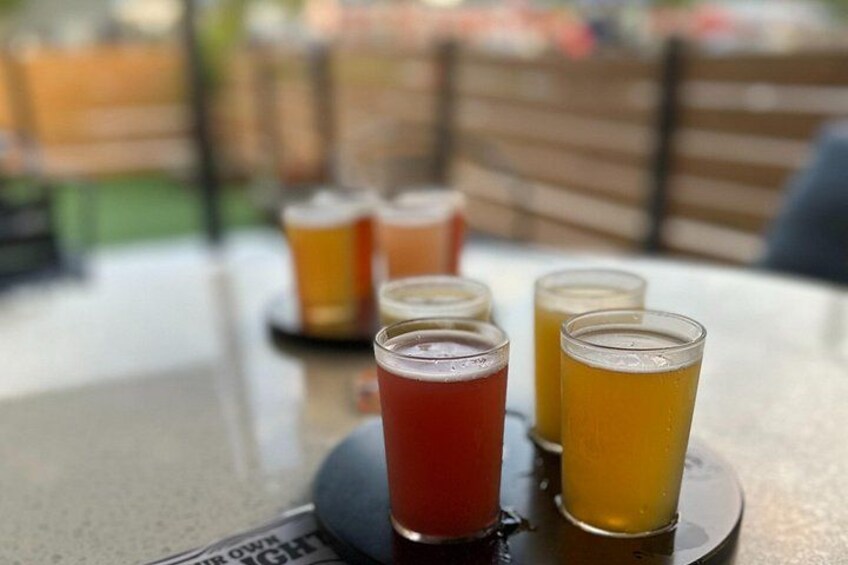 A table with four glasses of beer, one red and three yellow, on a coaster. 4
