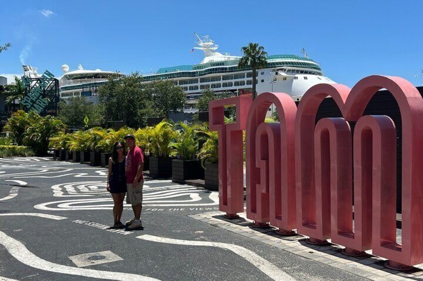 A cruise ship docked at a port with a large red sign reading 'TAMOON'. 2