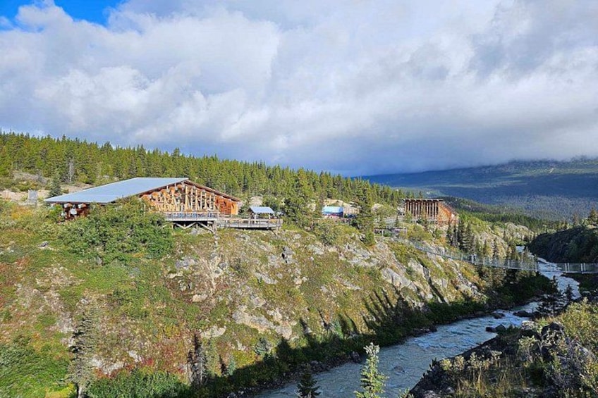 Un chalet au revêtement extérieur en bois, situé près d’une rivière et offrant une vue sur un paysage montagneux. 2