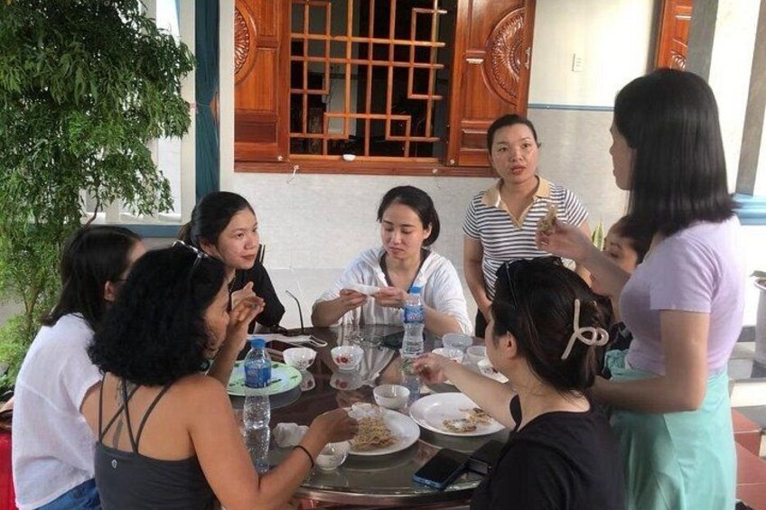 Un groupe de personnes est assis autour d’une table à l’extérieur, en train de discuter et de manger. 4