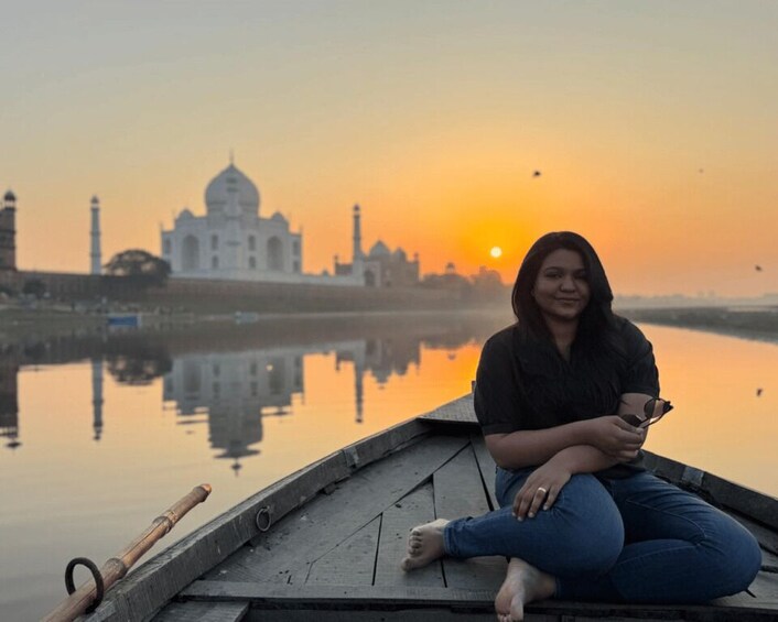 Une personne assise sur un bateau, avec le Taj Mahal en arrière-plan, au coucher du soleil. 2