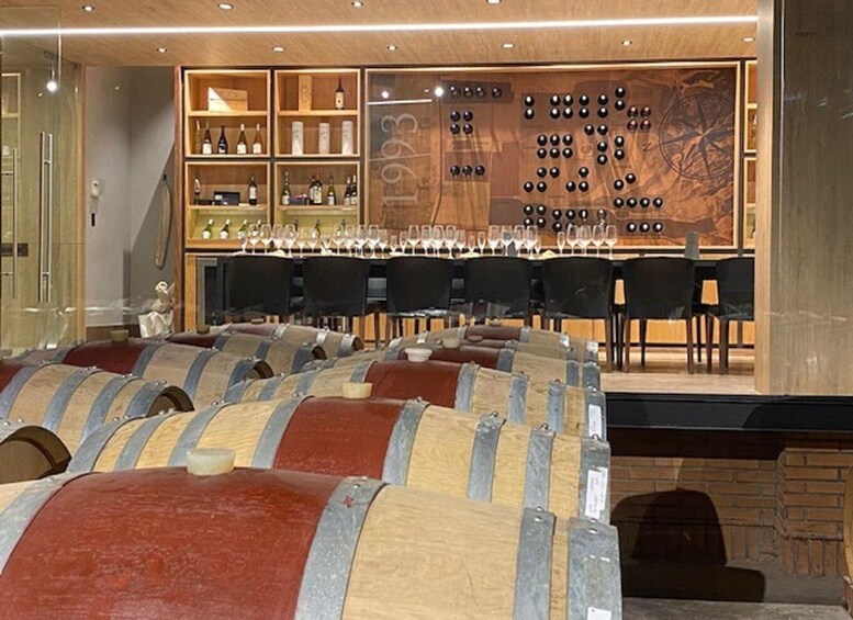 A wine cellar with wooden barrels and shelves of wine bottles. 1