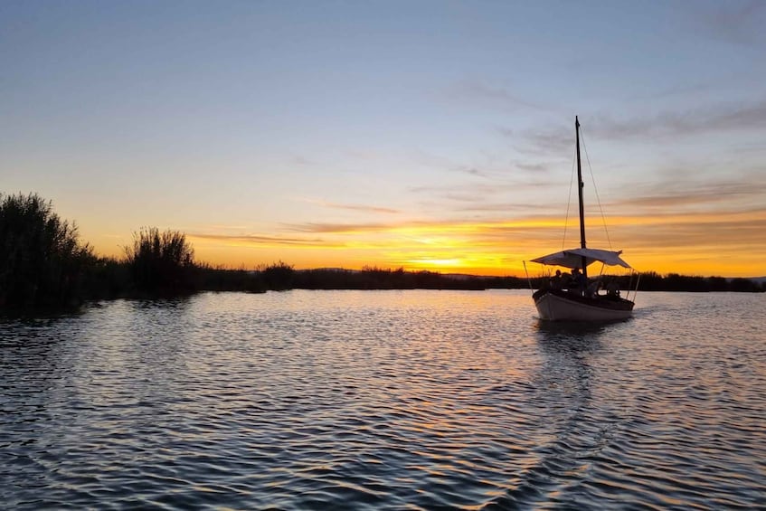 A sailboat on calm water during sunset. 1