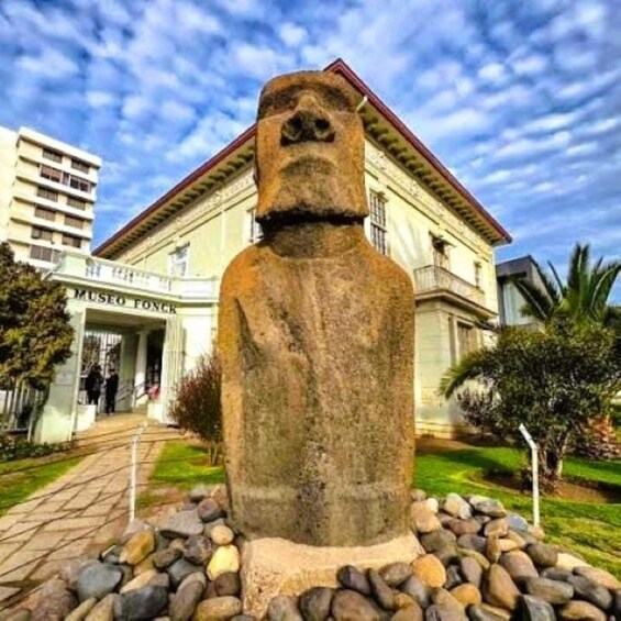 Een Moai-beeld voor een museum, onder een heldere lucht. 5