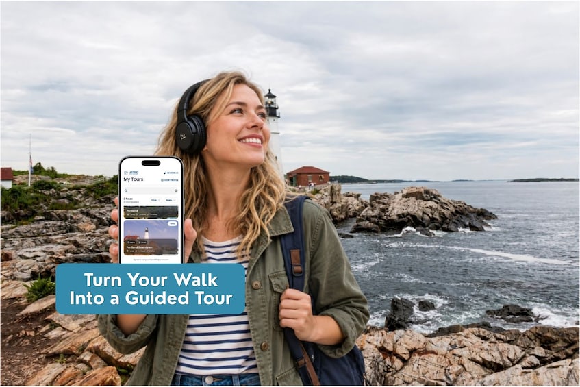 Eine Person hält ein Smartphone mit einer Reise-App auf dem Bildschirm, steht an einer felsigen Küste mit einem Leuchtturm im Hintergrund. 3