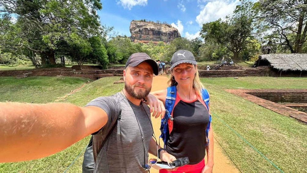 Two people taking a selfie with a large rock formation in the background. 2
