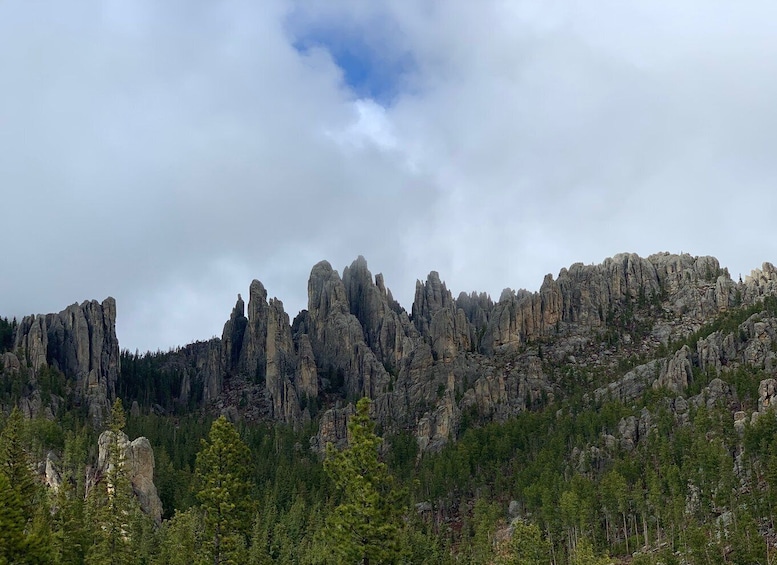 A rugged mountain landscape with prominent rock formations and dense forest. 4
