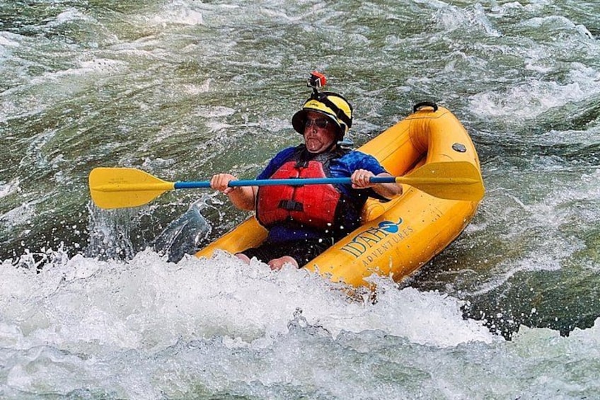 A person kayaking in a yellow raft on a river. 2