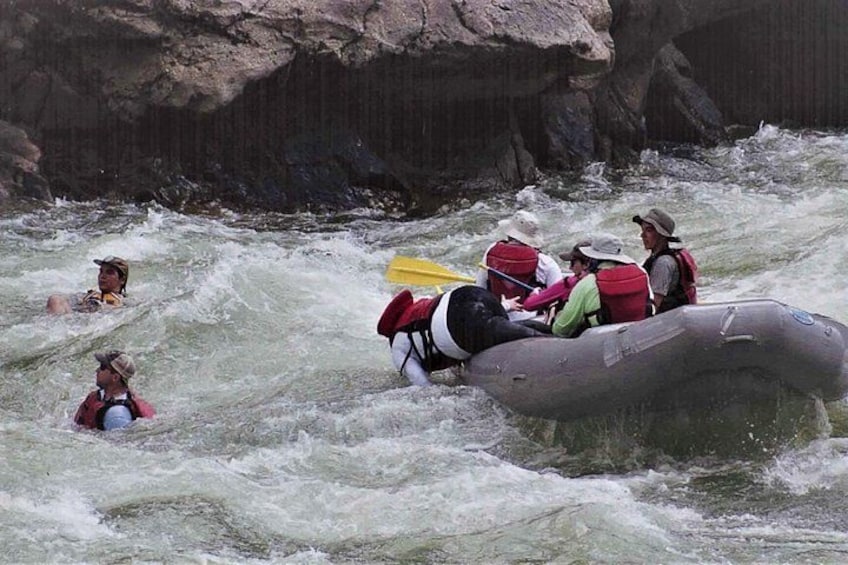 A group of people rafting on a river with rapids. 4