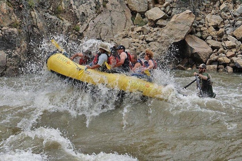A group of people in a yellow raft navigating through a river with rapids. 1