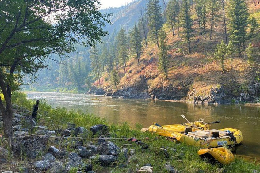 A river with a yellow raft, surrounded by trees and rocky terrain. 3