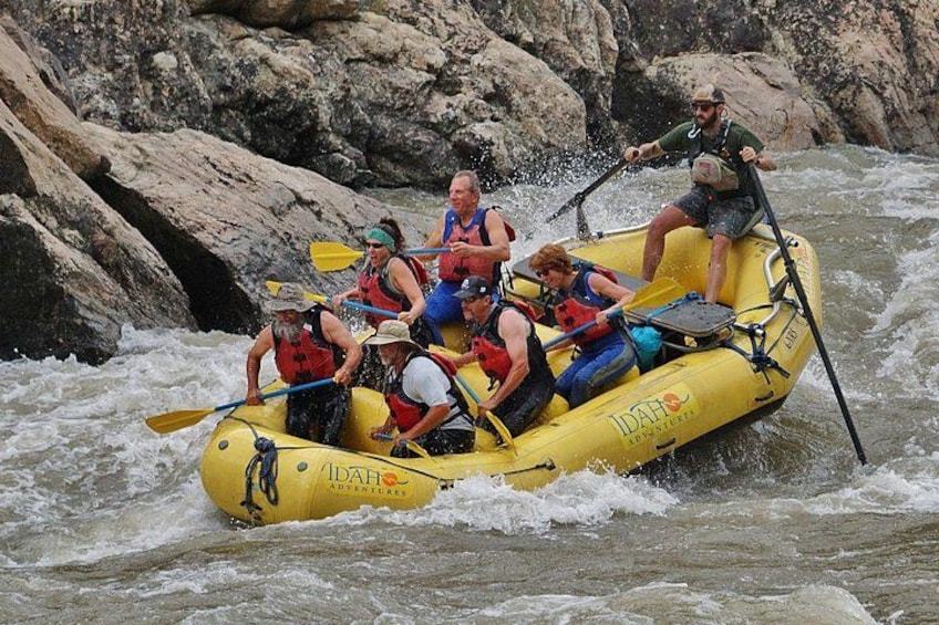 A group of people in a yellow raft navigating a river. 5
