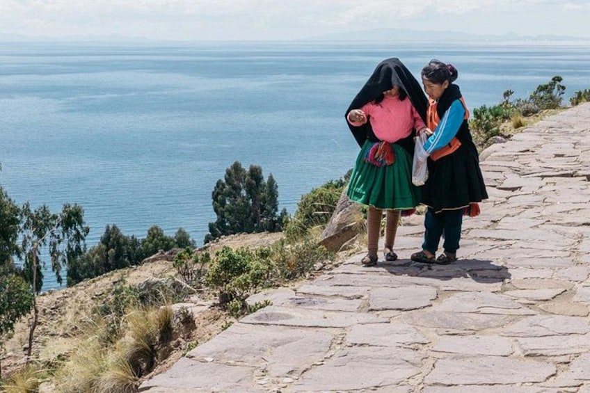 Dos personas se encuentran sobre un sendero de piedra con vistas a un cuerpo de agua. 3