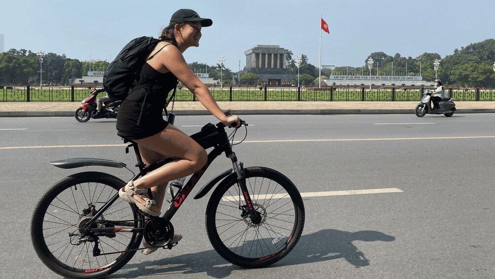 A person riding a bicycle on a road with a monument and flag in the background. 5