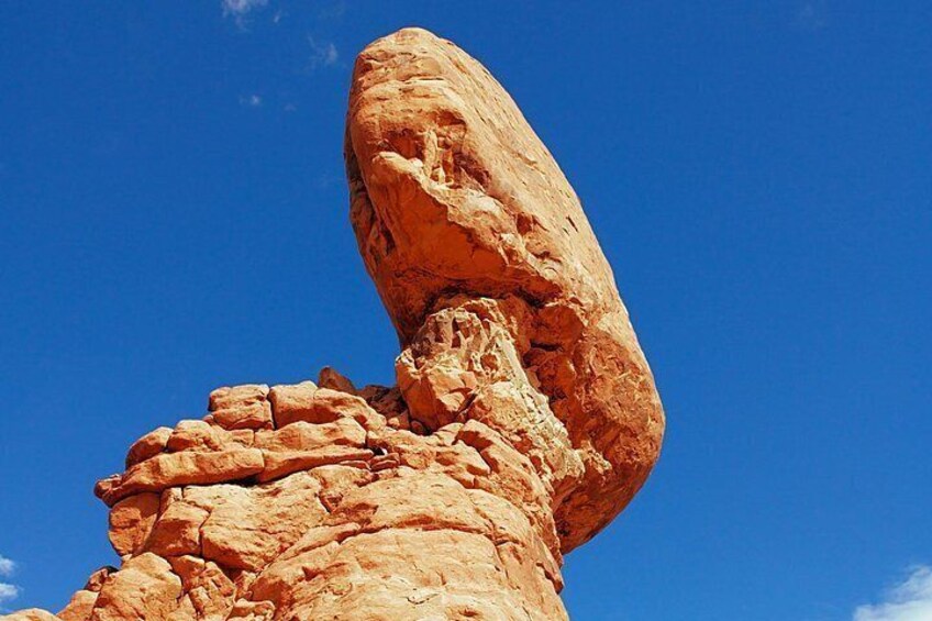 A large rock formation with a balanced overhang against a clear blue sky. 4