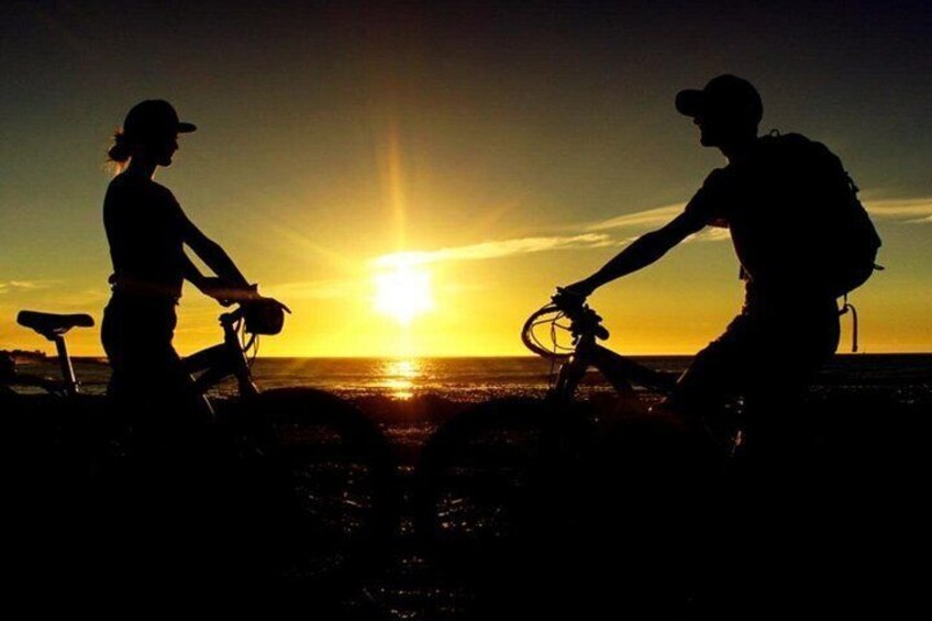 Two silhouettes of people on bicycles against a sunset. 3
