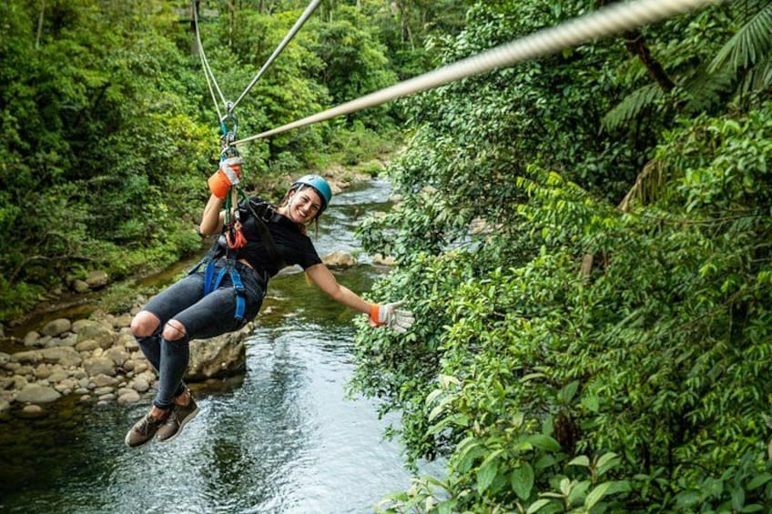 A person zip-lining over a river, surrounded by dense greenery. 1