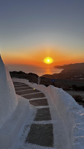 Ein Sonnenuntergang über einer Küstenlandschaft mit einer Treppe, die zum Meer hinabführt. 2