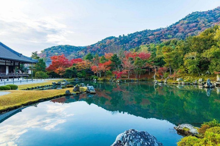 A tranquil pond surrounded by autumn foliage, a traditional building, and a mountainous backdrop. 3