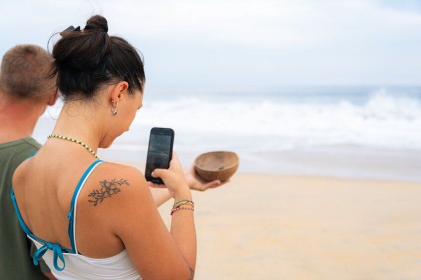 Une personne tenant un téléphone intelligent et un bol sur une plage. 4