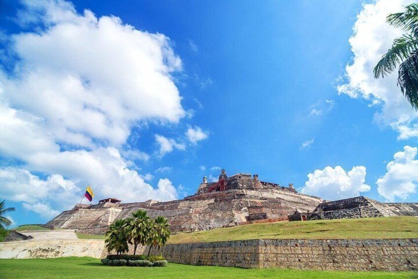 A historical site with ruins, a flag, and a clear sky. 2
