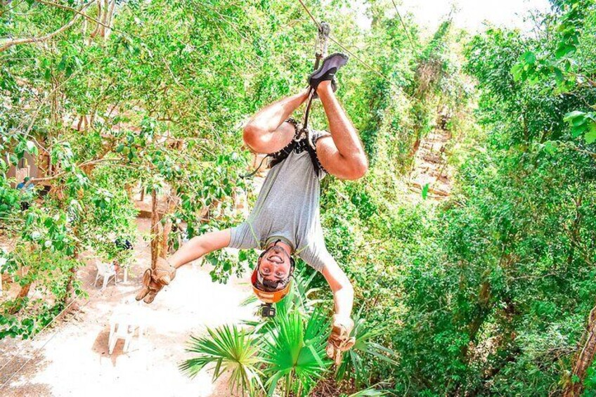 A person hanging upside down from a rope in a forested area. 2