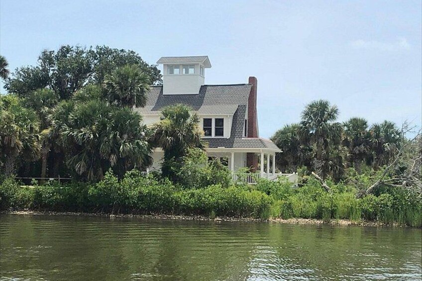 A house by a calm river with lush greenery and palm trees. 5