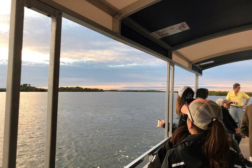 A group of people on a boat, looking out at a body of water with a distant shoreline. 2