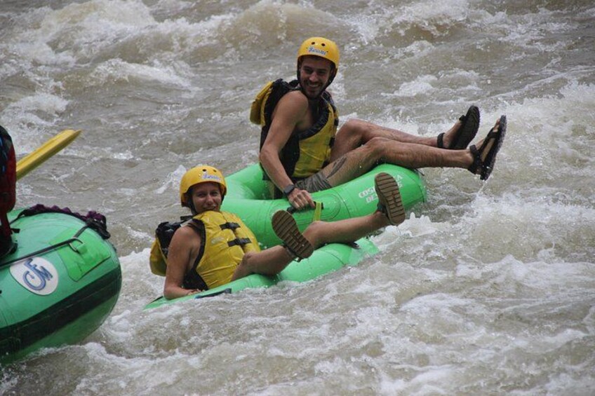 Two people rafting on a green inflatable raft in turbulent water. 2