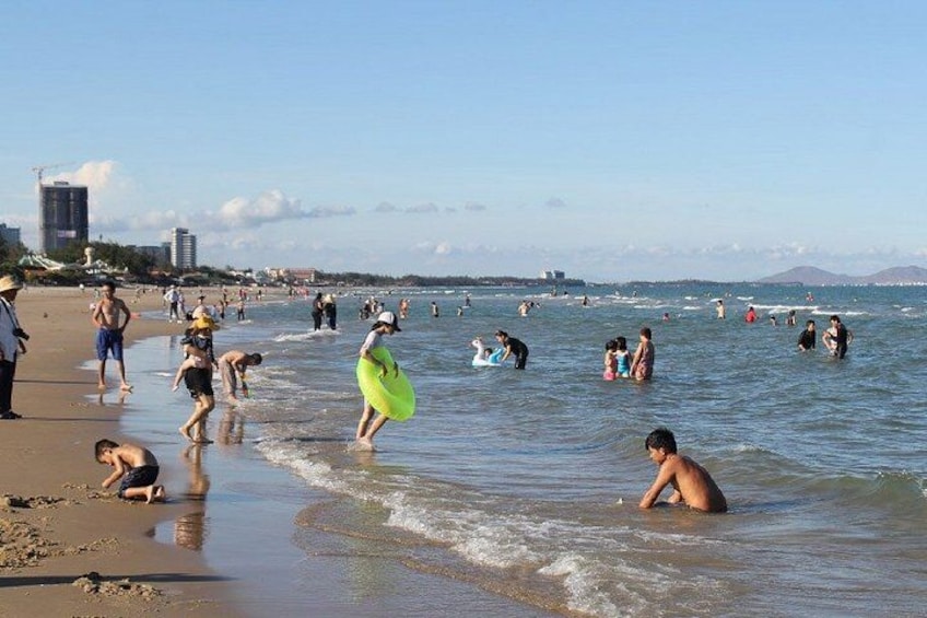Una playa concurrida con gente nadando y jugando en el agua. 5