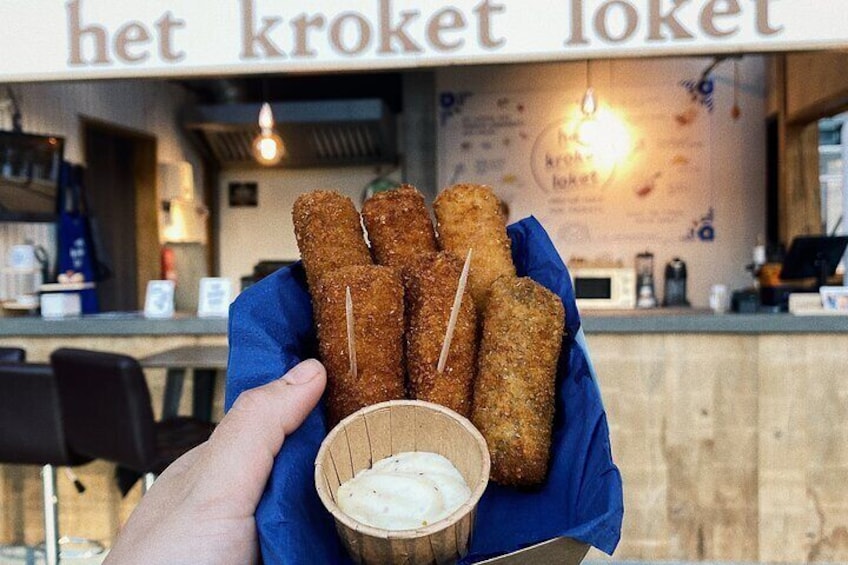 Een hand die een mandje met gebakken snacks vasthoudt, met saus erbij. 4