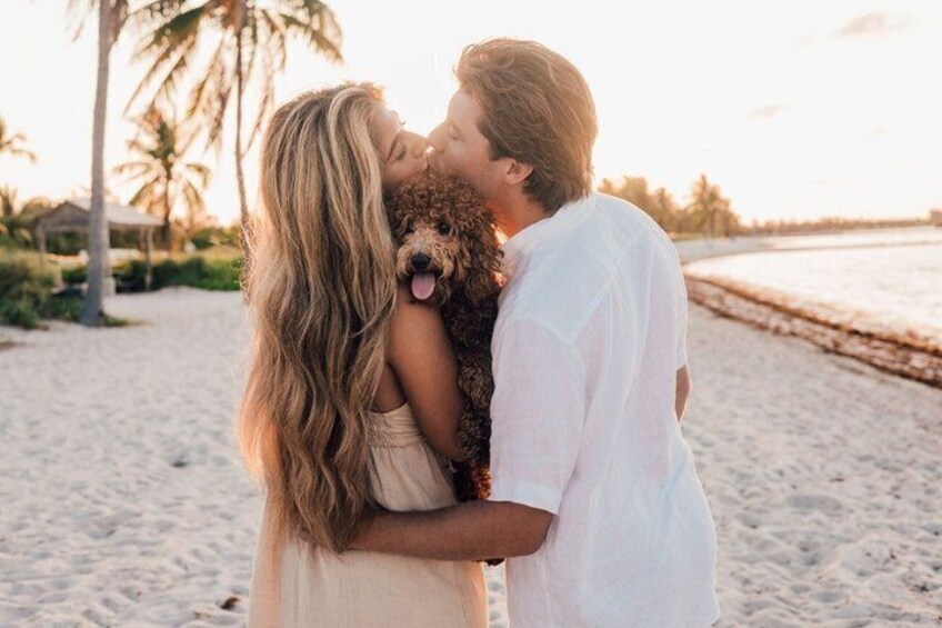 A couple embracing on a beach with palm trees and a sunset in the background. 4