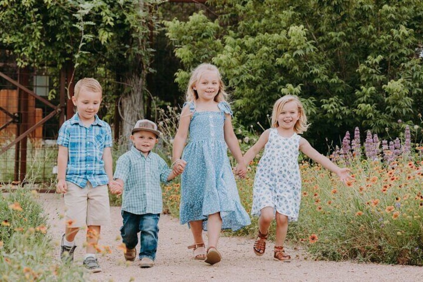 Barn som går längs en grusstig omgiven av grönska och blommor. 4