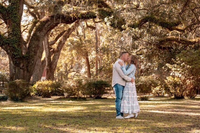 Una pareja abrazándose en un parque con árboles grandes y césped. 2