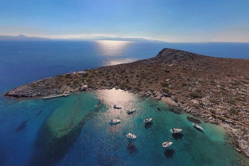 Un paisaje costero con aguas turquesas cristalinas, barcos anclados cerca de la orilla y una colina rocosa al fondo. 2