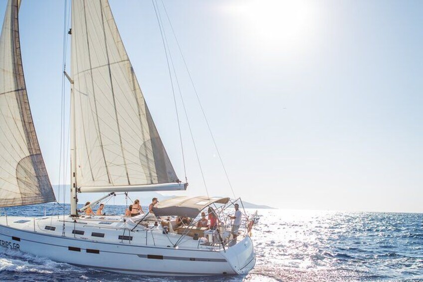 A sailboat with multiple sails on a calm sea under a clear sky. 5